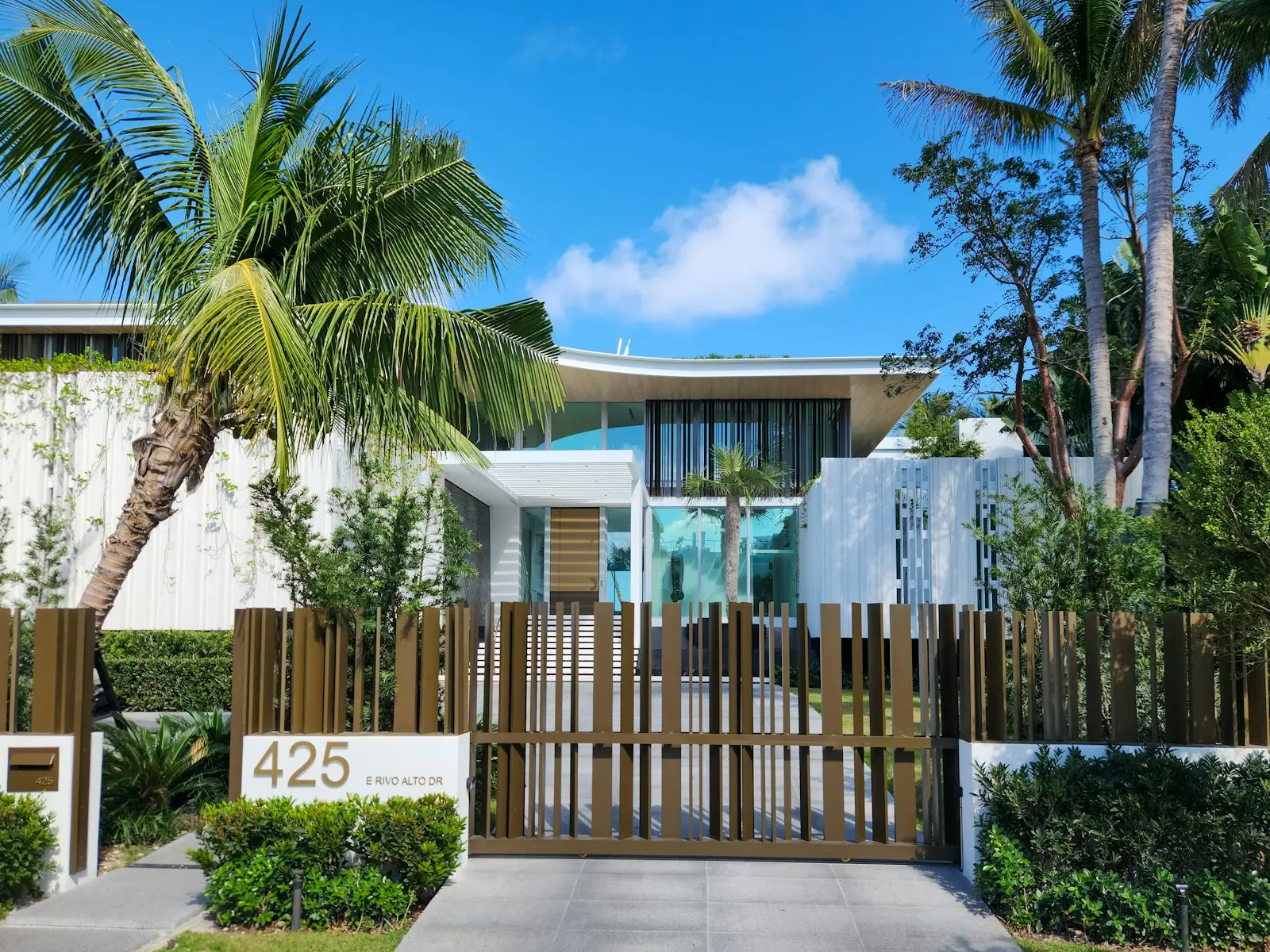 Modern single-family home behind a wood fence and palm trees