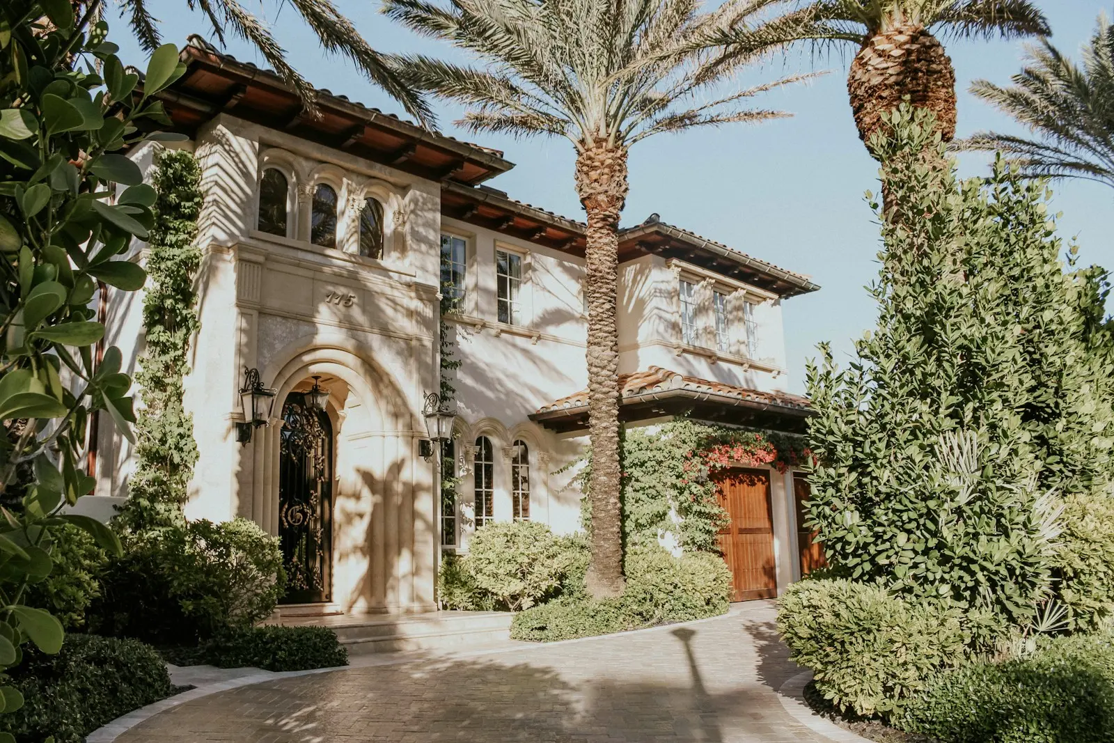Mediterranean-style home with palm trees and lush landscaping