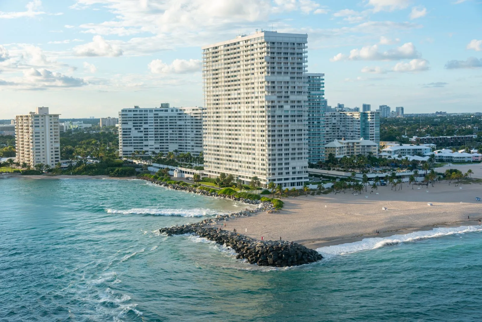 Aerial view of oceanfront towers, a beach and a rock jetty in Bal Harbour