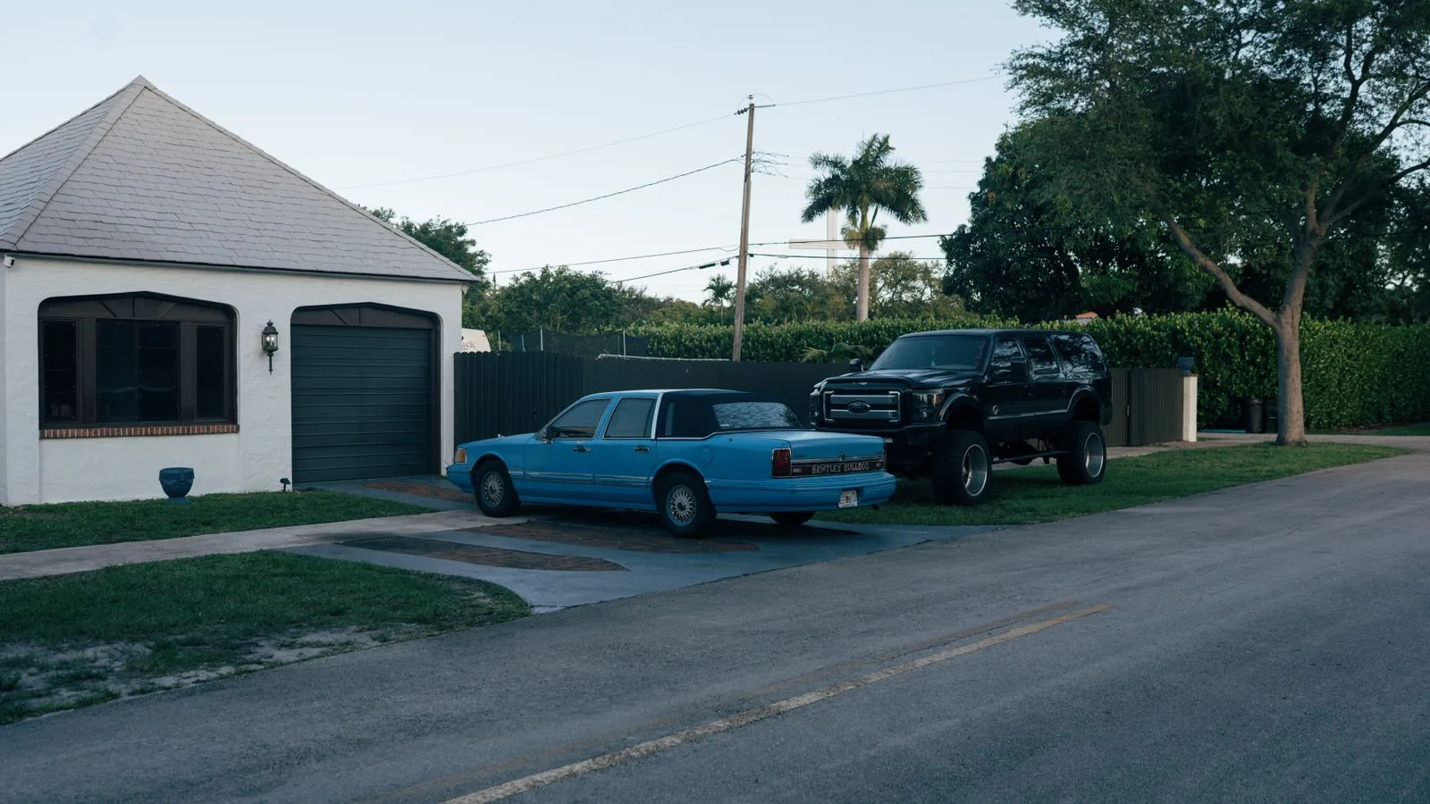 Single-story home with a garage and parked cars on a quiet residential street