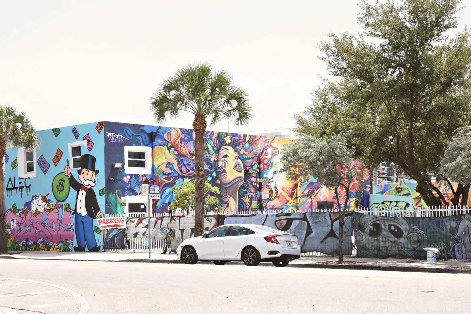 Building covered in colorful murals, with palm trees, in Miami
